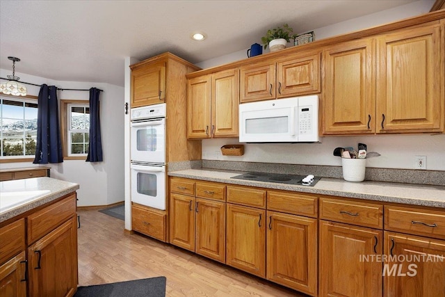 kitchen with brown cabinetry, white appliances, light countertops, and light wood-style flooring