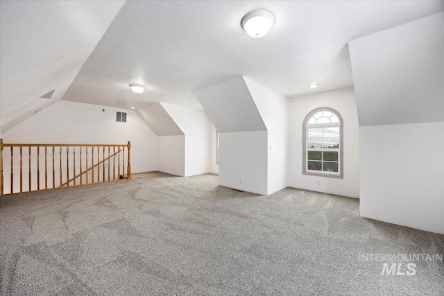 bonus room with carpet floors, visible vents, vaulted ceiling, and a textured ceiling