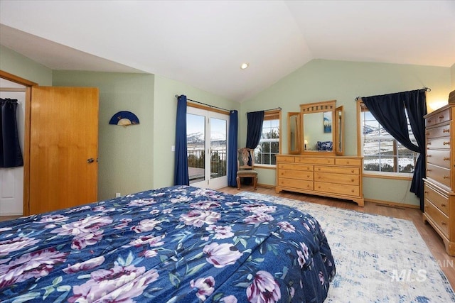 bedroom with access to exterior, lofted ceiling, multiple windows, and wood finished floors