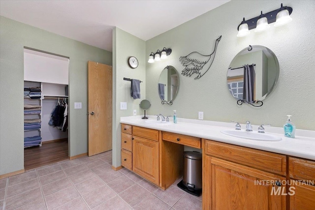 bathroom with tile patterned flooring, a walk in closet, a sink, and double vanity