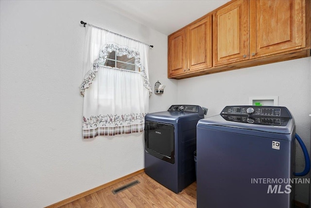 laundry area featuring visible vents, baseboards, light wood-type flooring, cabinet space, and washer and clothes dryer