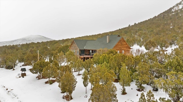 snowy aerial view with a mountain view and a wooded view