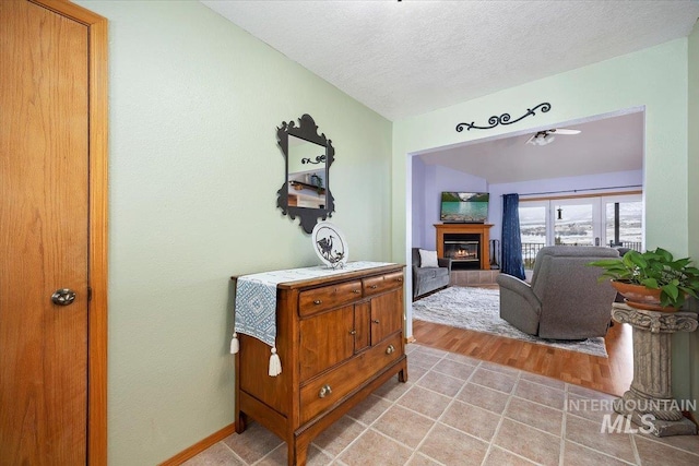 interior space featuring light wood-type flooring, a textured ceiling, and baseboards