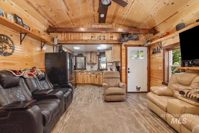 living area with wooden walls, a ceiling fan, vaulted ceiling with beams, and light wood-style floors