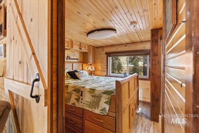 bedroom with light wood finished floors, wooden walls, and wooden ceiling