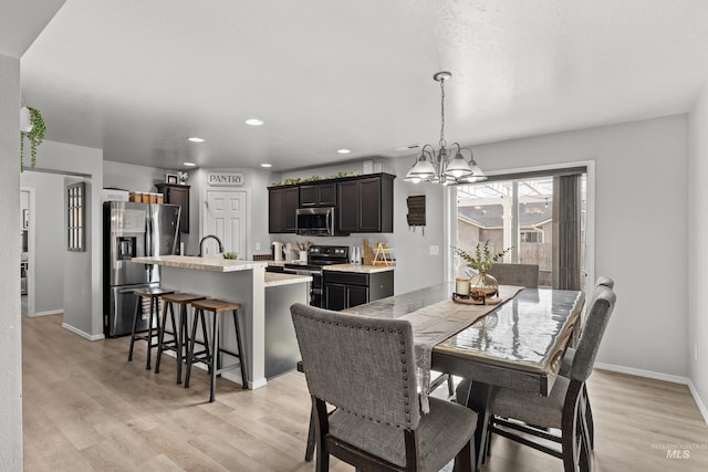 dining area with a chandelier, light wood finished floors, recessed lighting, and baseboards
