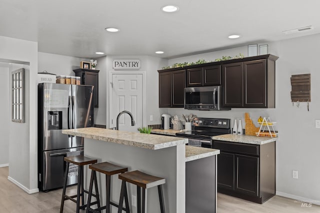 kitchen featuring stainless steel appliances, light countertops, light wood finished floors, baseboards, and recessed lighting