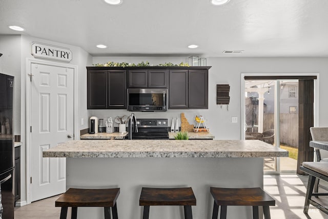kitchen with appliances with stainless steel finishes, light countertops, a breakfast bar area, and recessed lighting