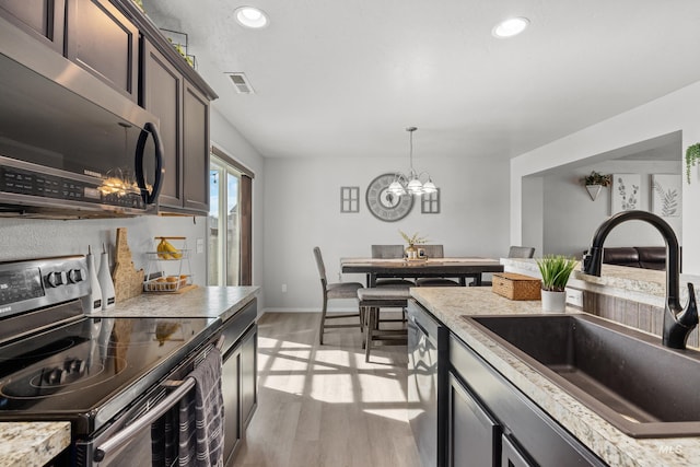 kitchen with stainless steel appliances, a sink, light wood-style flooring, recessed lighting, and light countertops