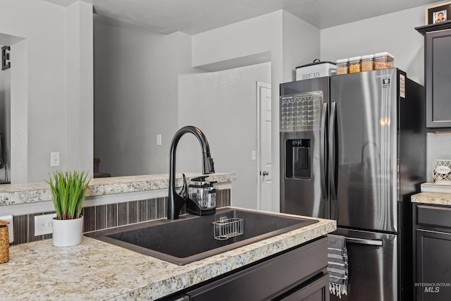 kitchen with stainless steel fridge with ice dispenser, a sink, and light countertops