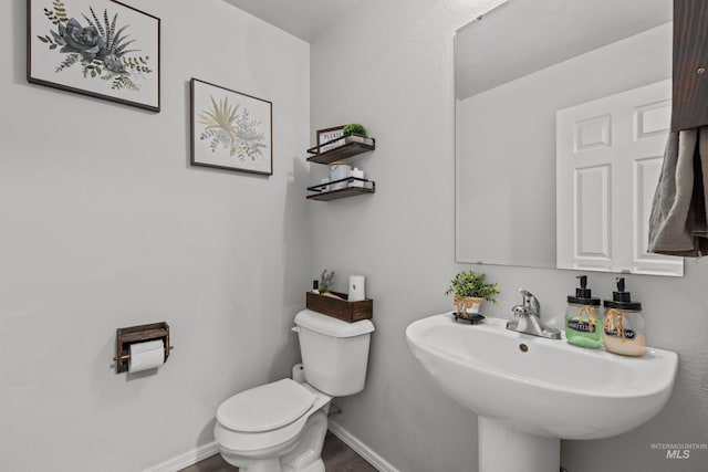 bathroom with a sink, toilet, baseboards, and wood finished floors