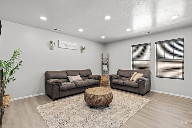 living room with light wood-type flooring, baseboards, and recessed lighting