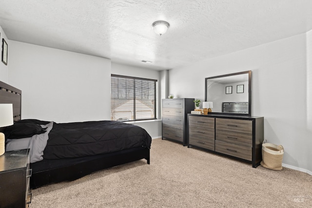bedroom with light carpet, baseboards, and a textured ceiling