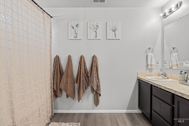 bathroom with vanity, wood finished floors, a shower with curtain, and baseboards