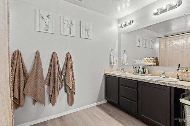 full bathroom with wood finished floors, double vanity, and baseboards