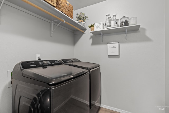 washroom featuring washing machine and clothes dryer, wood finished floors, and baseboards