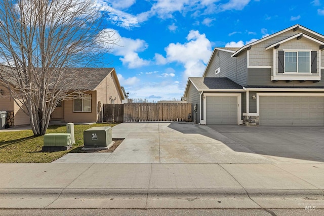 view of side of property with driveway, fence, stone siding, and an attached garage