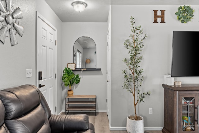 sitting room with wood finished floors, arched walkways, and baseboards