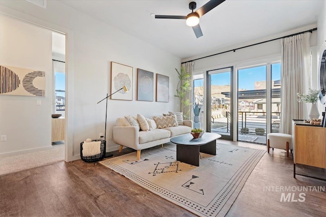 living room featuring a ceiling fan, baseboards, and wood finished floors