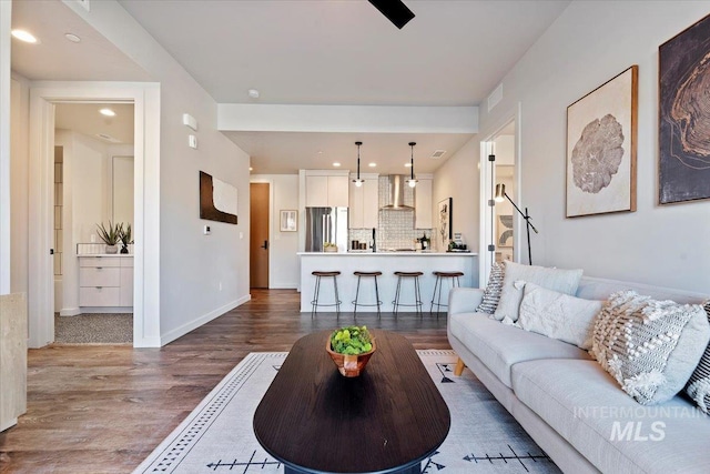 living room featuring recessed lighting, wood finished floors, visible vents, and baseboards