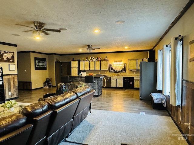 living room with ornamental molding, ceiling fan, a textured ceiling, and wood finished floors