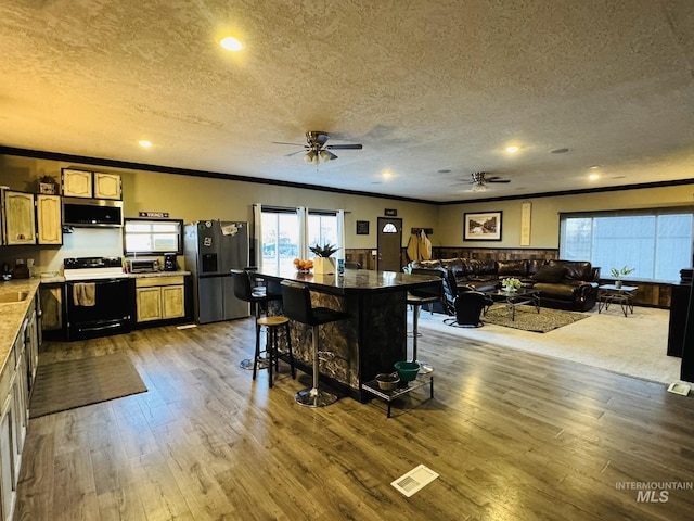 kitchen featuring stainless steel appliances, crown molding, dark wood finished floors, and a textured ceiling