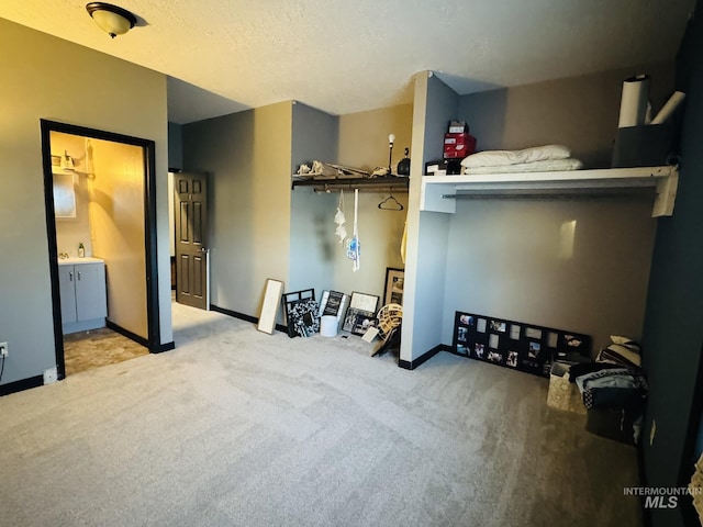 carpeted bedroom with a sink, baseboards, and ensuite bathroom