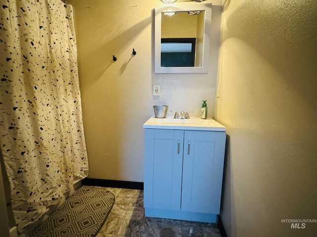 full bath with curtained shower, vanity, and baseboards