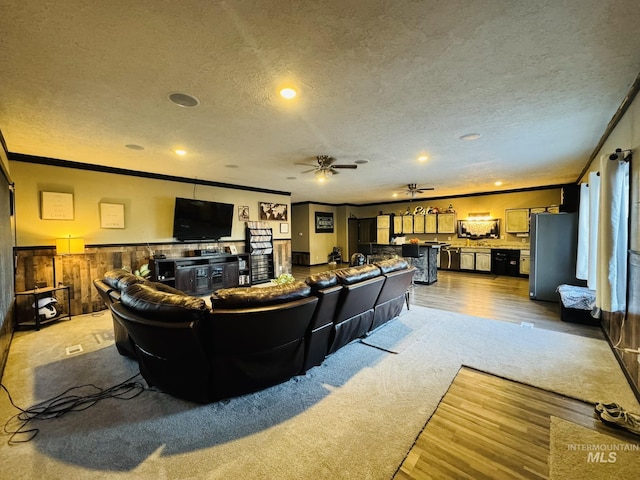 living area with ornamental molding, light wood-style floors, a textured ceiling, and a ceiling fan