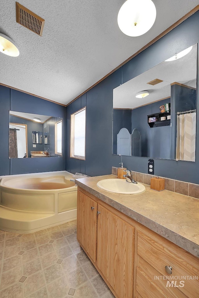 bathroom featuring tile patterned flooring, vanity, a bath, and a textured ceiling