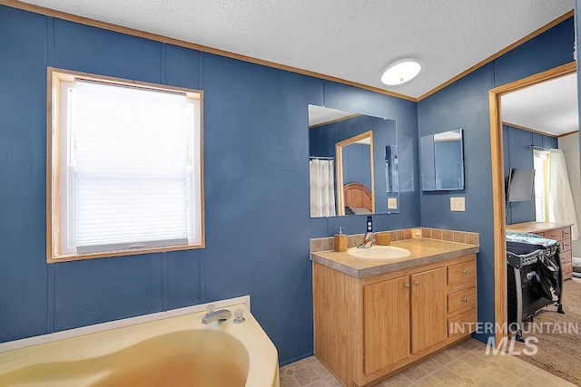 bathroom with vanity, a textured ceiling, and a tub