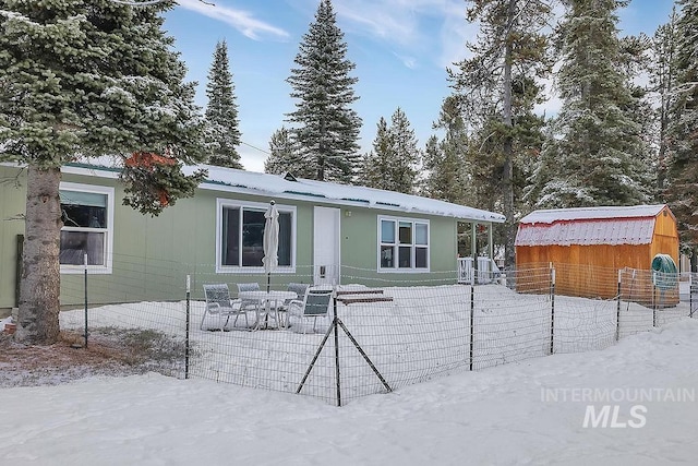 snow covered back of property featuring a shed