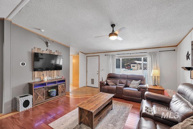 living room with lofted ceiling, hardwood / wood-style flooring, ceiling fan, ornamental molding, and a textured ceiling