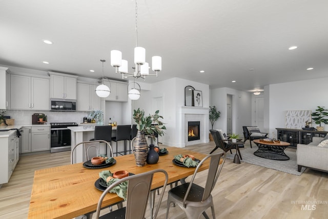 4541 E Fortuna Dr, Nampa, ID 83687 - dining area with recessed lighting, light wood-style floors, a warm lit fireplace, and a chandelier