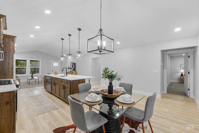 dining room featuring sink, an inviting chandelier, vaulted ceiling, and light hardwood / wood-style flooring