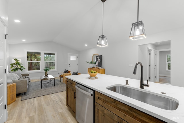 kitchen featuring decorative light fixtures, sink, stainless steel dishwasher, lofted ceiling, and light hardwood / wood-style flooring