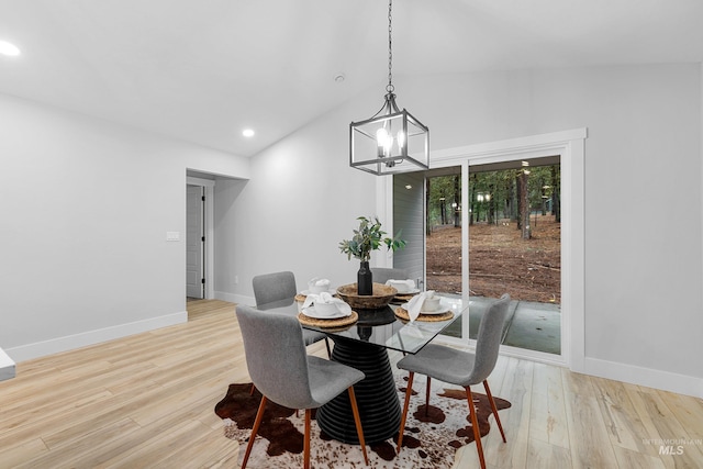 dining space featuring light hardwood / wood-style floors, an inviting chandelier, and vaulted ceiling