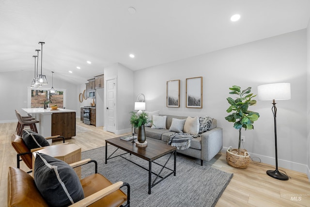 living room with sink, light hardwood / wood-style flooring, and lofted ceiling