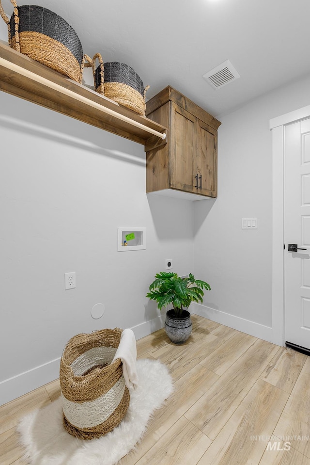 laundry area with hookup for a washing machine, electric dryer hookup, wood-type flooring, and cabinets