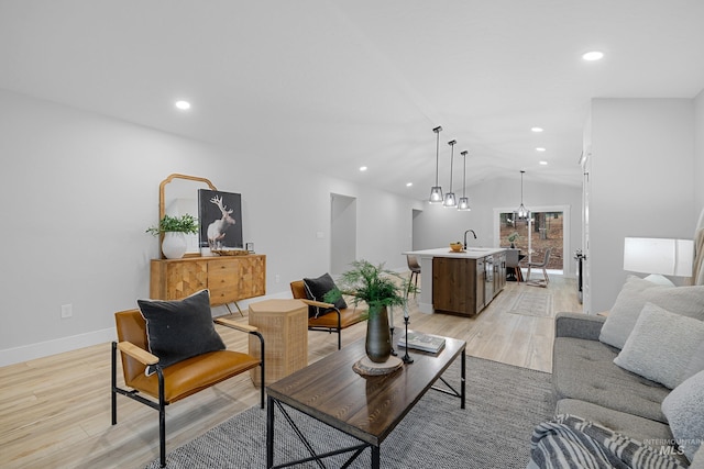 living room with light hardwood / wood-style floors, sink, and lofted ceiling