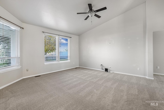 carpeted spare room with a ceiling fan, a healthy amount of sunlight, lofted ceiling, and visible vents