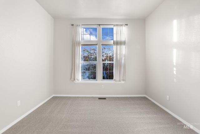 carpeted empty room featuring baseboards and visible vents