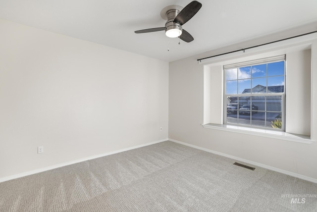 carpeted empty room featuring baseboards, ceiling fan, and visible vents