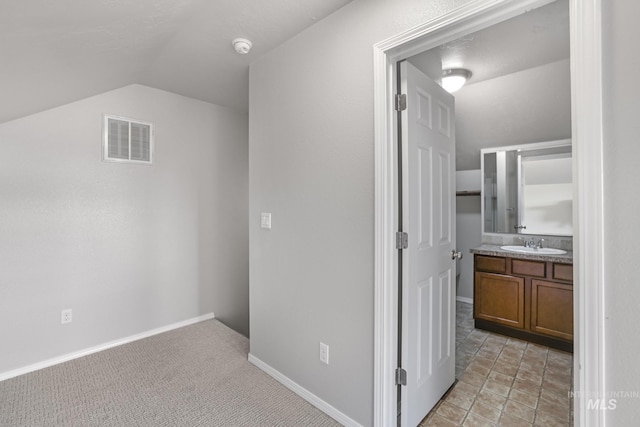 additional living space featuring visible vents, baseboards, a sink, vaulted ceiling, and light colored carpet