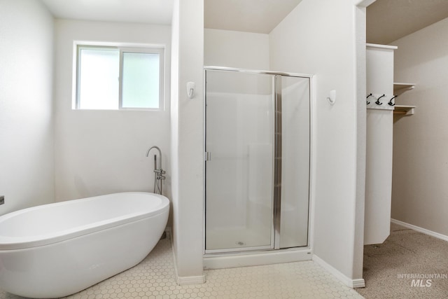 bathroom featuring baseboards, a freestanding tub, tile patterned flooring, and a shower stall