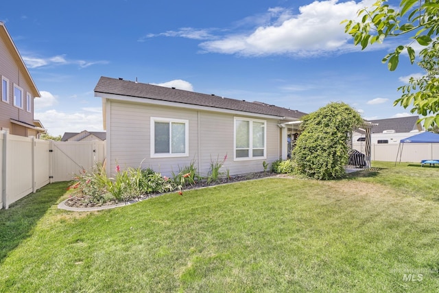 rear view of house featuring a fenced backyard and a yard
