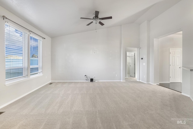 spare room with visible vents, baseboards, a ceiling fan, vaulted ceiling, and light colored carpet