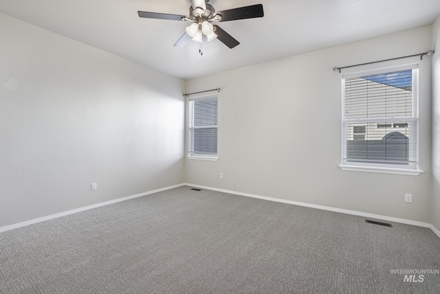 empty room with baseboards, visible vents, carpet flooring, and a ceiling fan