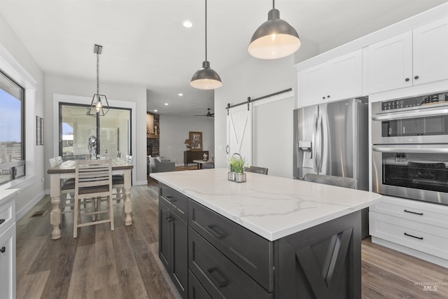 518 Bass Run Ln, Marsing, ID 83639 - kitchen featuring stainless steel appliances, a barn door, white cabinets, dark cabinets, and dark wood-style floors