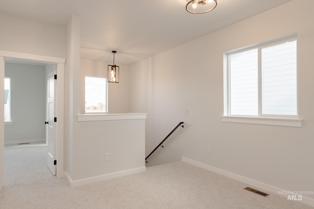 interior space featuring carpet floors, baseboards, visible vents, and an upstairs landing